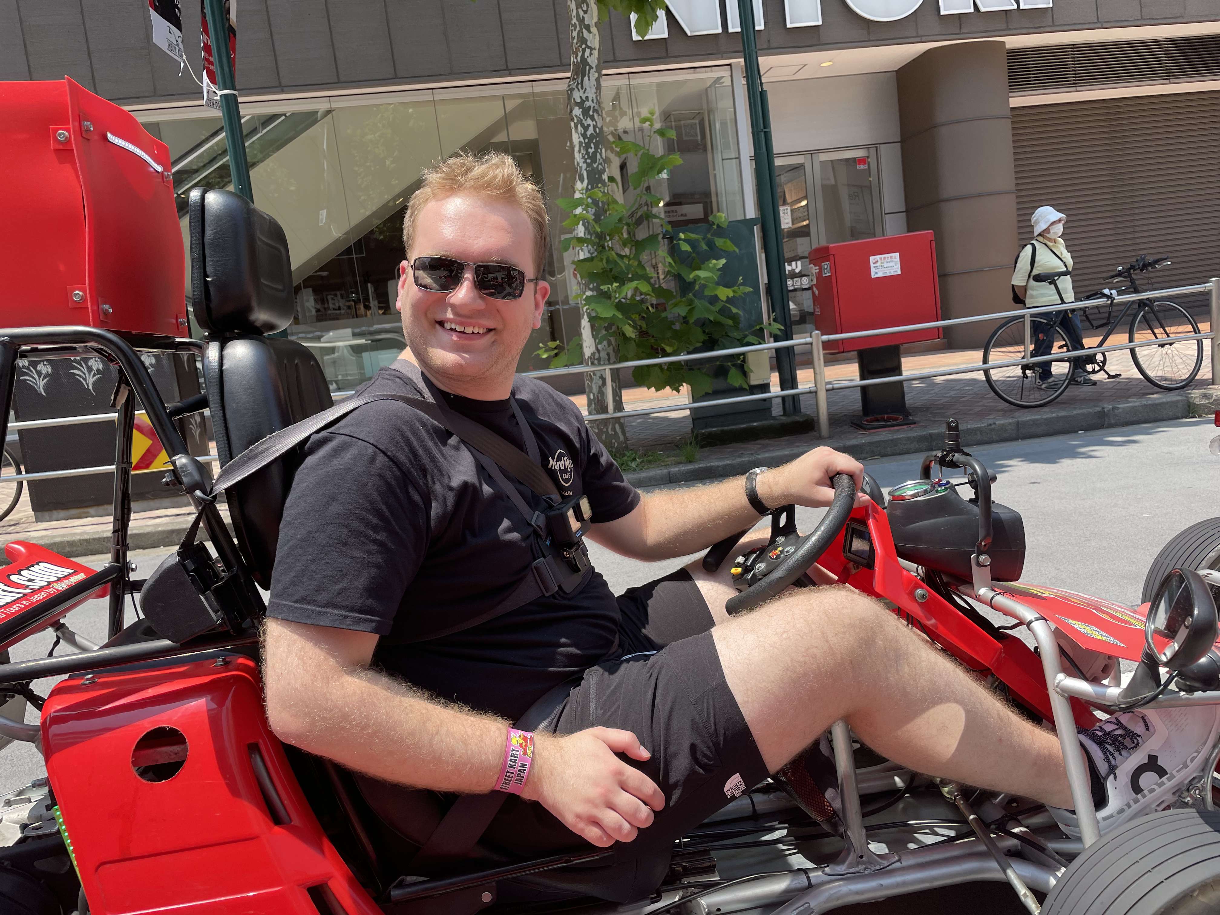 Ryan Smith smiling while driving a red go-kart in Japan.