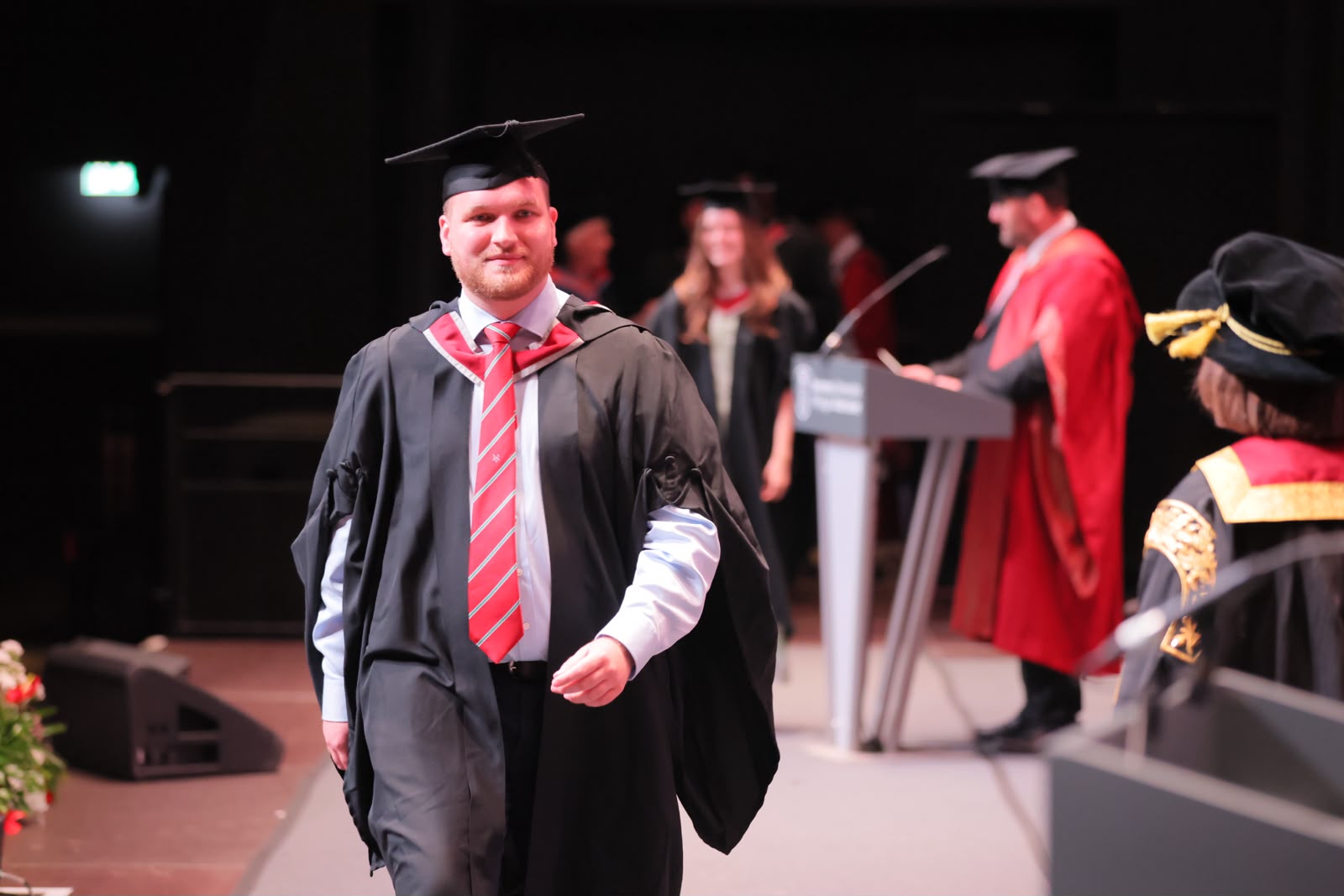 Ryan Smith walking across the graduation stage at Swansea University.
